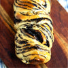 Braided eggless Dark Chocolate Babka with chocolate swirls on a wooden board