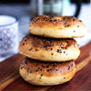 Stack of three bagels with sesame seeds on a wooden surface