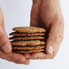 Stack of almond flour chocolate chip cookies held between two hands against a white background