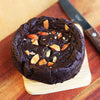 Eggless Almond Fudge Brownie topped with roast almonds on a wooden board.
