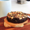 Freshly baked gluten free almond flour brownie topped with crushed almond praline on a wooden board.