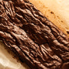 Close up of a crackly topped dark chocolate brownie loaf on a wooden board