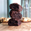 Stack of three fudge brownies on a wooden surface with blurred background