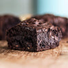 Close-up of a chocolate fudge brownie on a wooden surface with blurred background