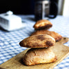 A stack of two freshly baked vegan Ciabatta bread on a wooden board with a chequered table cloth
