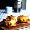 Three eggless classic cinnamon rolls on a wooden board with a blurred background