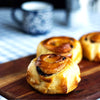 Three eggless classic cinnamon rolls on a wooden board with a blurred background