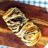 Braided eggless Dark Chocolate Babka with chocolate swirls on a wooden board with chequered table cloth in background