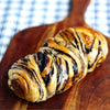 Braided eggless Dark Chocolate Babka with chocolate swirls on a wooden board
