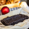 An eggless almond fudge brownie loaf on a white table cloth against a blurred background