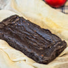 An eggless almond fudge brownie loaf on a white table cloth against a blurred background