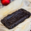 An eggless almond fudge brownie loaf on a white table cloth against a blurred background