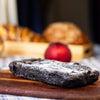 An eggless almond fudge brownie loaf on a white table cloth against a blurred background