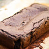 Close-up of a fudgy gluten free dark chocolate brownie loaf on a white surface