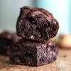 Two fudgy gluten free brownies stacked on top of each other with a blurred background