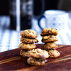 A stack of eggless mini chocolate chip cookies on a wooden board against a blurred background