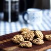 A pack of eggless mini chocolate chip cookies on a wooden board against a blurred background