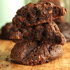 Stack of new york style chocolate almond praline cookies on a wooden surface with a blurred background