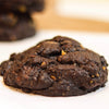 Close-up of a new york style  chocolate almond praline cookie on a white surface with a blurred background
