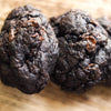 Close-up of two new york style dark chocolate chip cookies on a wooden surface
