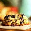 Close-up of a New York Style Rum Raisin and Nut Cookie on a wooden board with a blurred background