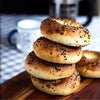 Stack of bagels with sesame seeds on a wooden cutting board with a blurred background