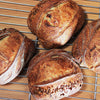 Loaves of sourdough bread on a cooling rack with a wooden surface