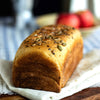 Artisanal whole wheat sandwich bread with seeds on a wooden board with a blurred background