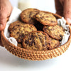 Basket of chocolate chip cookies held by a person on a white background