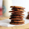 Stack of freshly baked eggless chocolate chip cookies on a white paper with a blurred background