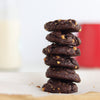 Stack of dark chocolate brookies with nuts on a white surface