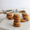 Stacks of Jaggery Butter cookies on a white surface with a blurred background.