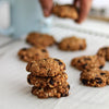Stack of oatmeal raisin cookies on a baking sheet with more cookies in the background.